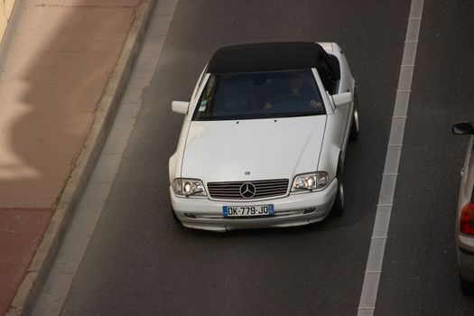 Monte-Carlo, Monaco - April 6, 2016: White Mercedes 300 SL in the Streets of Monaco. Man Driving a Mercedes 300 SL (1990) in the South of France