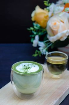 closeup cup of green tea latte on wooden plate