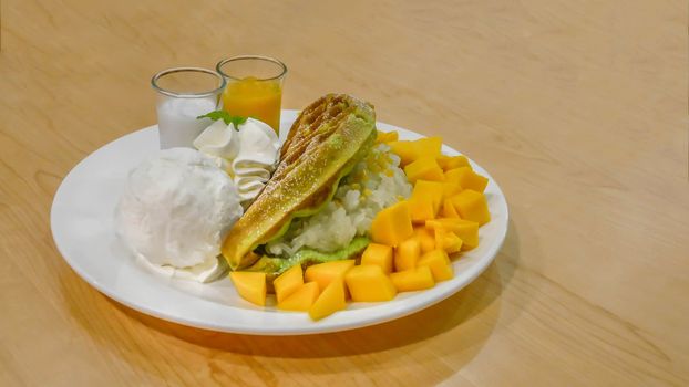 waffles served with ice cream , ripe mango and sweet sticky rice on plate