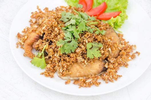fired fish with garlic and fresh vegetable on dish