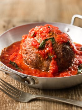 close up of rustic italian meatball in tomato sauce