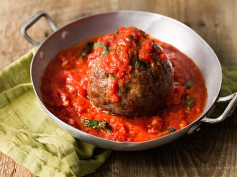 close up of rustic italian meatball in tomato sauce