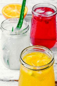 Three bottles of drinks from aloe,orange, and cranberries in a light tone