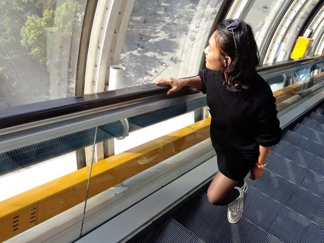 Young asian woman on elevator looking out