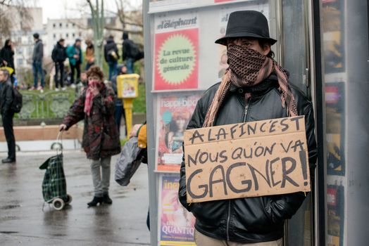 FRANCE, Paris: A demonstrator stands with a sign which reads A la fin c'est nous qu'on va gagner! during a protest on April 9, 2016 in Paris, against the French government's proposed labour law reforms.