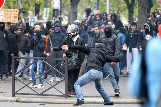 FRANCE, Paris: A protester throws an unidentifiable item to riot policemen rush during a demo on April 9, 2016 in Paris, against the French government's proposed labour law reforms.