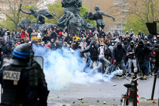 FRANCE, Paris: Riot policemen stand in front of protesters surrounded by tear gas during a demo on April 9, 2016 in Paris, against the French government's proposed labour law reforms.