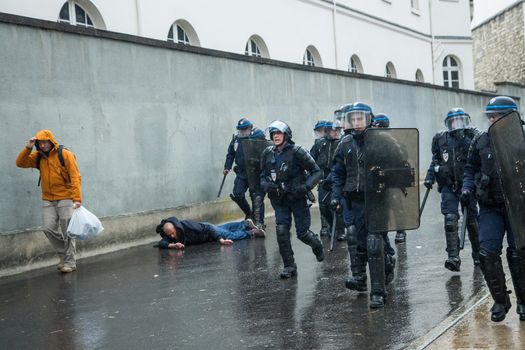 FRANCE, Paris: A protester lays on the ground surrounded by policemen during a demo on April 9, 2016 in Paris, against the French government's proposed labour law reforms.