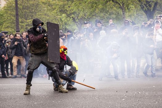 FRANCE, Paris: A protester stands behind a shield during clashes with riot police at the end of a demonstration against planned labour reforms, in Paris, France, on April 9, 2016.