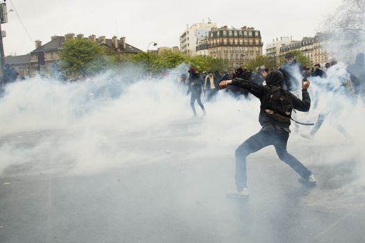 FRANCE, Paris: A protester throws an unidentifiable item to riot police at the end of a demonstration against planned labour reforms, in Paris, France, on April 9, 2016.