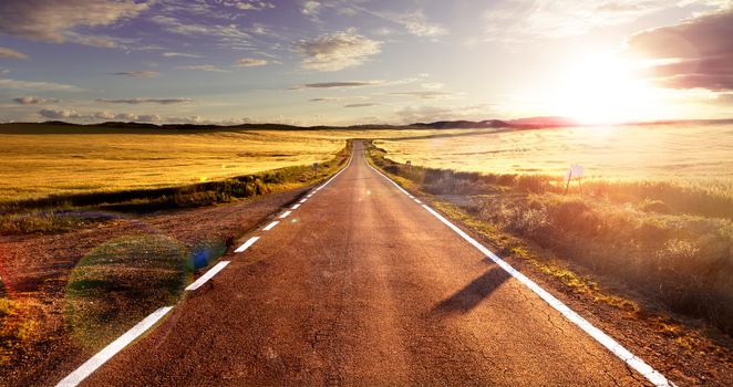 Adventures and road trips.Sunset and travel concept.Road and fields