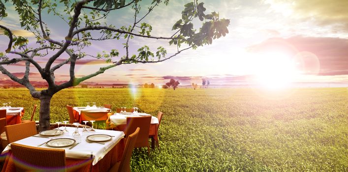 Idyllic outdoor restaurant in the green fields and sunset