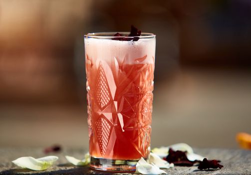 Singapore Sling in the sunlight with rose petals. Shallow dof