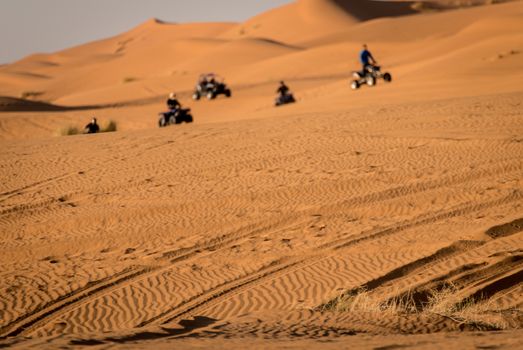 Quads and buggys riding through Sahara Desert dunes. Morroco.