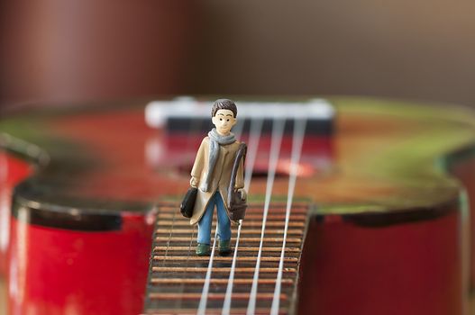 Miniature figurine, artist walking on a guitar