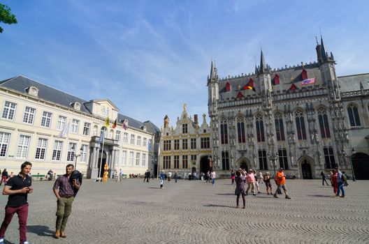 Bruges, Belgium - May 11, 2015: Tourist on Burg square with City Hall in Bruges, Belgium on May 11, 2015. The historic city centre is a prominent World Heritage Site of UNESCO.