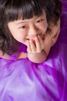 A portrait of a cute, happy and young Japanese girl in a purple dress.