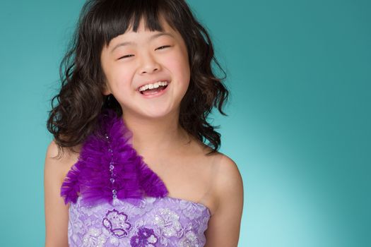 A portrait of a cute, happy and young Japanese girl in a purple dress on a blue background.