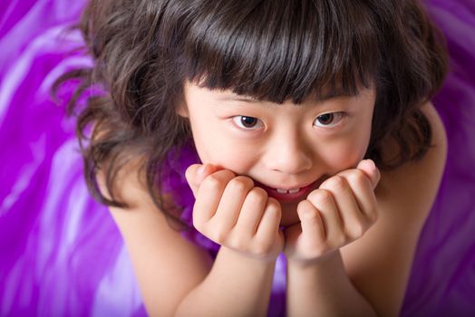 A portrait of a cute, happy and young Japanese girl in a purple dress.