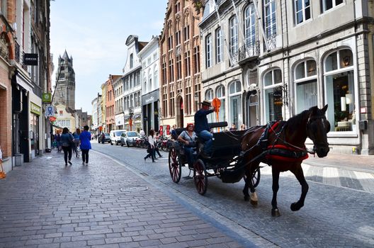 Bruges, Belgium - May 11, 2015: Tourists visit Bruges in traditional horse carriage around the city. Bruges is the capital and largest city of the province of West Flanders in the Flemish Region of Belgium.