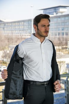 Head and Shoulders Portrait of Stylist Young Man Wearing Suit and Hat Looking to the Side Out Window While Standing on Moving Sidewalk in Building