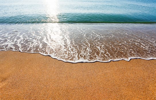 Sun light reflected on soft wave of the sea on the sandy beach