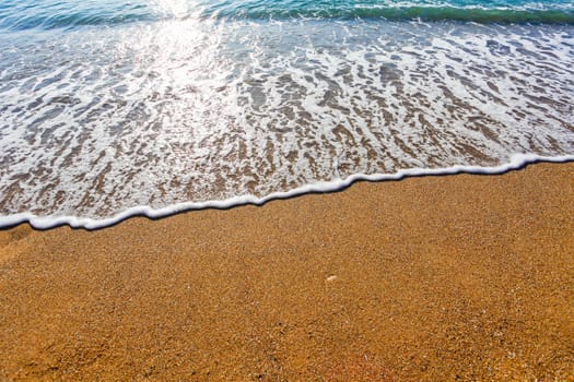 Sun light reflected on soft wave of the sea on the sandy beach