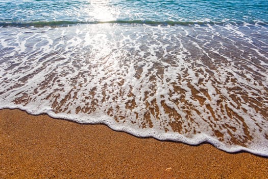 Sun light reflected on soft wave of the sea on the sandy beach