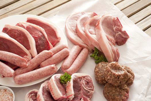 Table made of wooden slats set with a diverse selection of meat cuts and sausage links