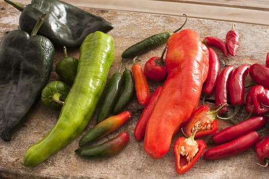 Large assortment of freshly picked green and red hot peppers displayed on a rustic table