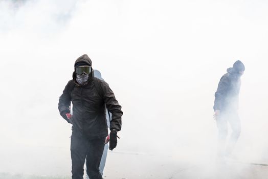 FRANCE, Paris: A protester walks through the smoke during a demonstration on April 9, 2016 in Paris, against the French government's proposed labour law reforms.