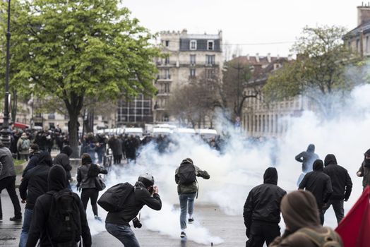 FRANCE, Paris: A protester walks through the smoke during a demo on April 9, 2016 in Paris, against the French government's proposed labour law reforms.