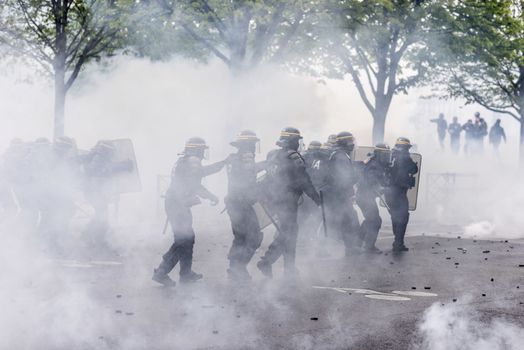 FRANCE, Paris : Riot policemen run over a protesters during a demonstration against labour reform in Paris on April 9, 2016.