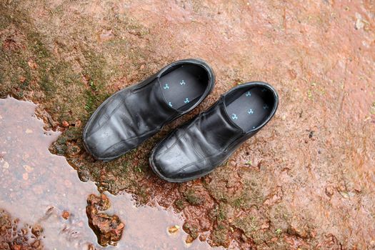 Black leather shoes abandoned on a rock in a camping trial