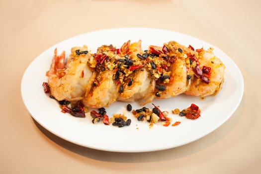 Fried shrimp with spices on dish .