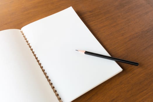 Blank note book with pencil on wooden table background concept and Idea for write your text here.