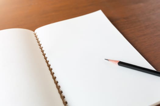 Blank note book with pencil on wooden table background concept and Idea for write your text here.