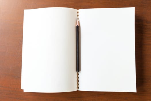 Blank note book with pencil on wooden table background concept and Idea for write your text here.