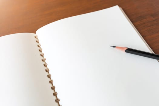 Blank note book with pencil on wooden table background concept and Idea for write your text here.