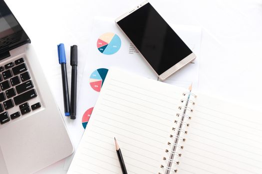 Blank note book with pencil pen laptop and smartphone on white table concept and Idea for write your text here.