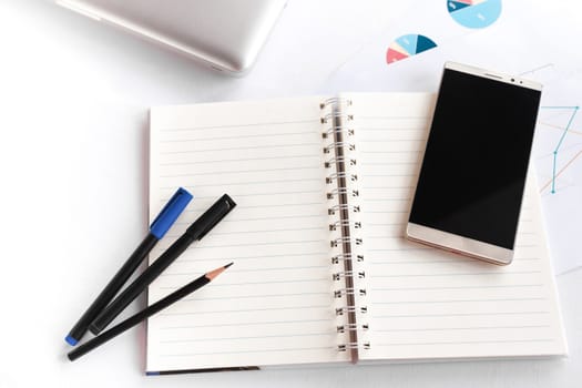 Blank note book with pencil pen laptop and smartphone on white table concept and Idea for write your text here.