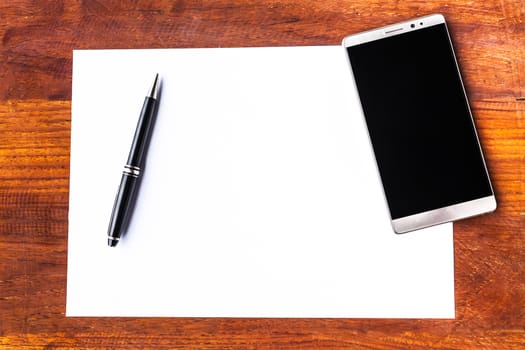 Blank paper with pen and smartphone on wood table concept and Idea for write your text here.