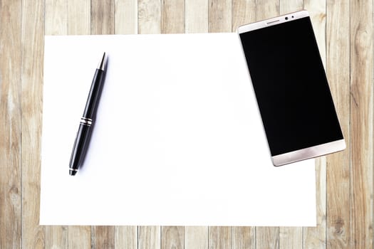 Blank paper with pen and smartphone on wood table concept and Idea for write your text here.