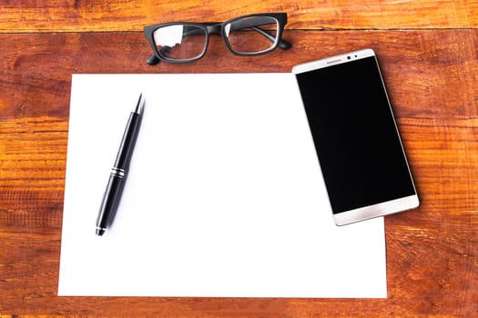 Blank paper with pen and smartphone on wood table concept and Idea for write your text here.