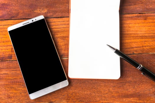 Blank paper with pen and smartphone on wood table concept and Idea for write your text here.