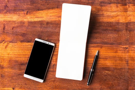 Blank paper with pen and smartphone on wood table concept and Idea for write your text here.