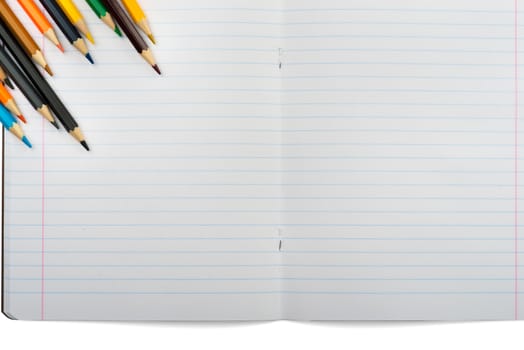 Open notebook with crayons on isolated white background, closeup