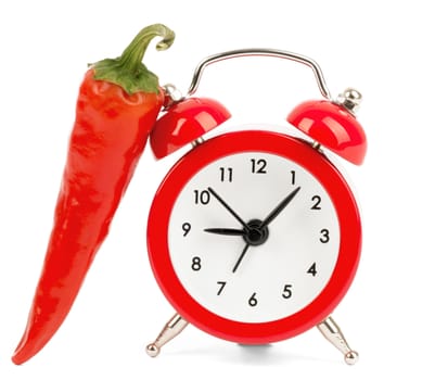 Red hot pepper with alarm clock on isolated white background