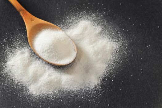 Bicarbonate in a wooden spoon on black background