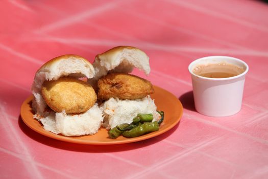 An Indian snack called Vada Pav which is like a potato burger or tikki n a bread, with a cup of tea